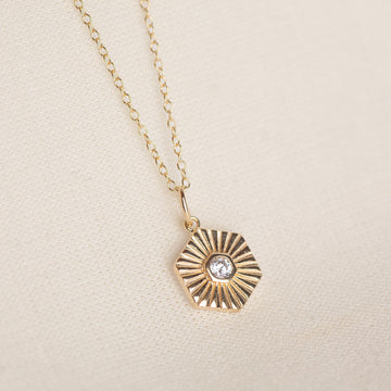 a gold necklace with a diamond on it