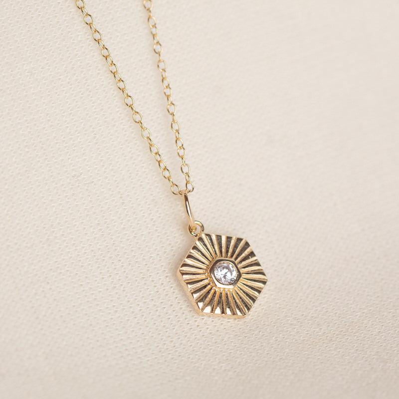 a gold necklace with a diamond on it