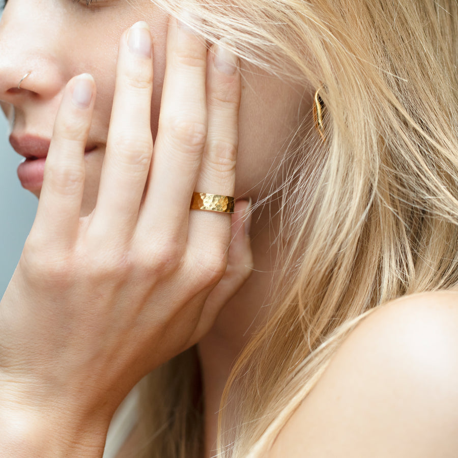 wide hammered gold band on model's finger